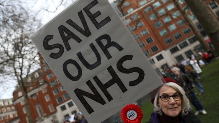امرأة تحمل لافتة للمطالبة بمزيد من التمويل لخدمة الصحة الوطنية البريطانية
