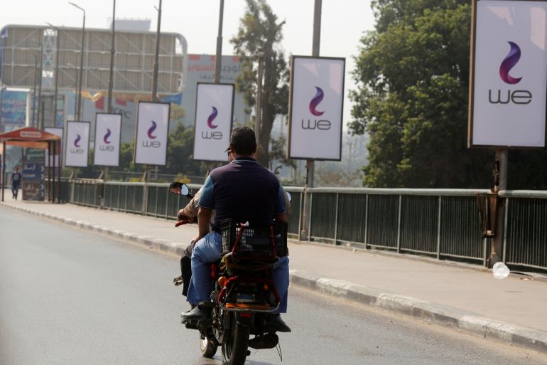 رجل مصري يركب دراجة نارية بالقرب من الشعار الجديد لمصر للاتصالات في القاهرة