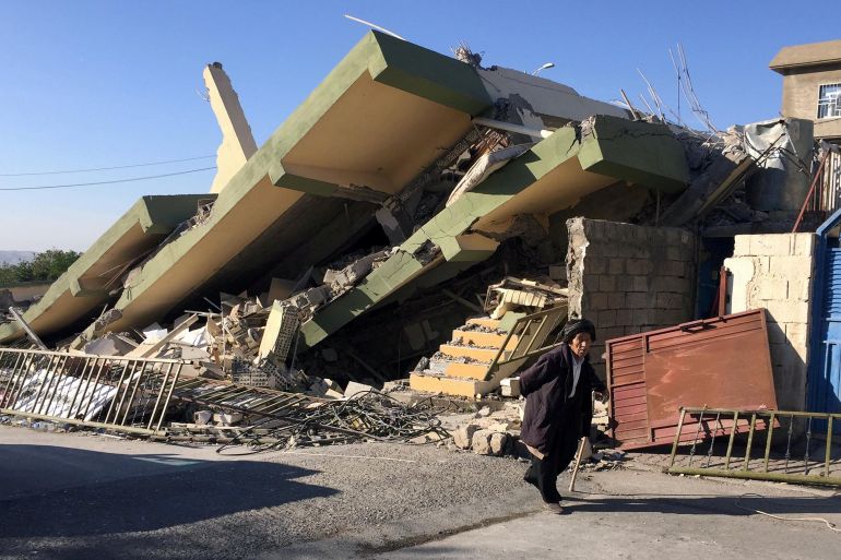 إيراني يسير بجانب بناية متهدمة جراء الزلزال الذي ضرب إيران