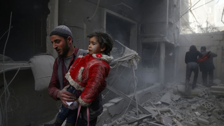 رجل يحمل طفلة بعد غارة جوية سورية على الغوطة الشرقية (أرشيفية) 