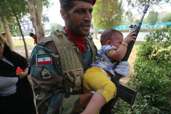 جندي إيراني يحمل طفلاً في موقع الهجوم على عرض عسكري في مدينة الأهواز جنوب غرب إيران