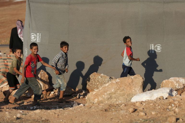 أطفال نازحون يركضون خارج خيمة في محافظة إدلب، سوريا