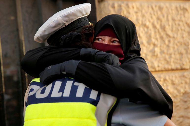 مرتدية النقاب تبكي وهي تُحتضن على يد "شرطية" دنماركية خلال مظاهرة ضد حظر الحجاب