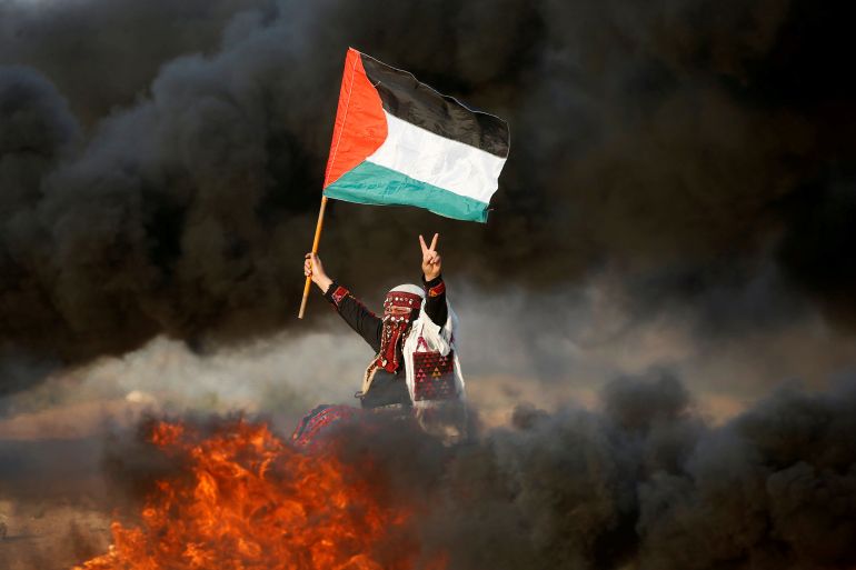 امرأة ترفع العلم الفلسطيني خلال مظاهرة تدعو إلى رفع الحصار الإسرائيلي عن غزة وتطالب بالحق في العودة