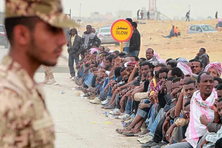 ضابط سعودي يقف أمام مجموعة من المهاجرين غير الشرعيين في الرياض