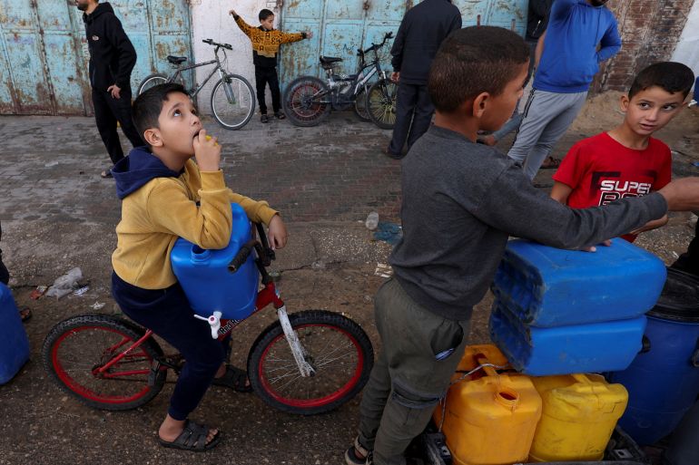 أطفال في غزة واقفين في طابور انتظارا للحصول على بعض مياه الشرب (رويترز)