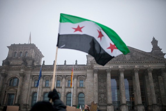 سوريون يلوحون بعلم بلادهم أمام مبنى البرلمان الألماني في العاصمة برلين