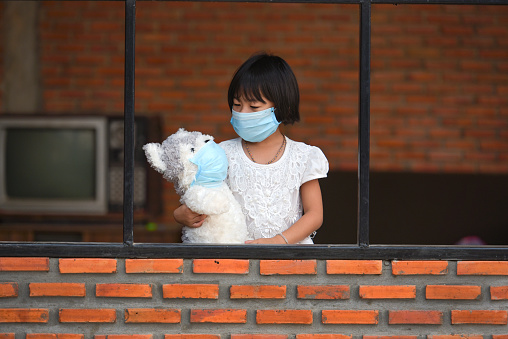 طفلة ترتدي كمامة واقية من فيروس كورونا المستجد وتضع أخرى لدميتها