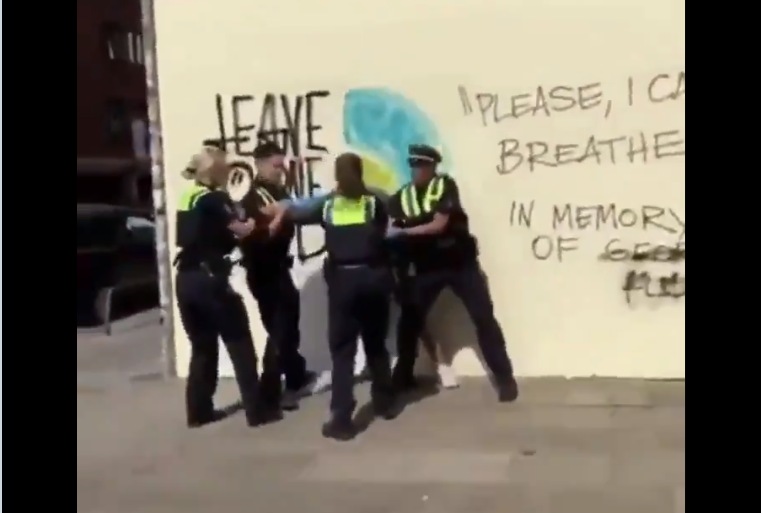 تظهر كلمات "لا أستطيع التنفس" الشهيرة على الحائط خلف الشاب أثناء اعتداء الشرطة عليه