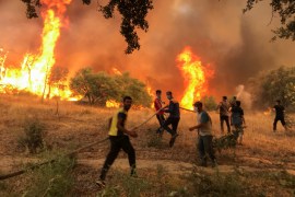 Villagers carry a hose as they try to put out a wildfire, in Achallam village