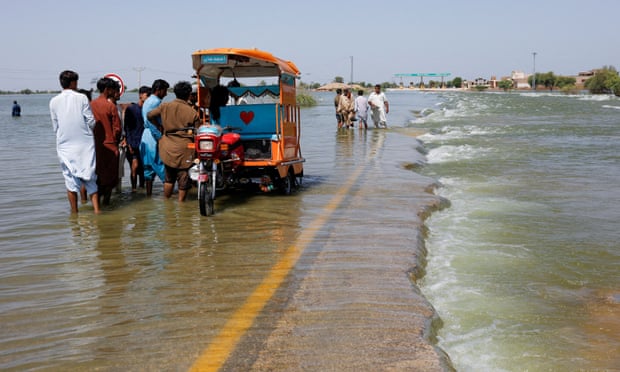 Displaced people stand on a flooded highway, following rains and floods during the monsoon season in Sehwan, Pakistan. Photograph: Akhtar Soomro/Reuters
