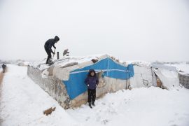 نازحون يزيلون الثلج في مخيم أعزاز بعد تساقط الثلوج في الأجزاء الشمالية من سوريا