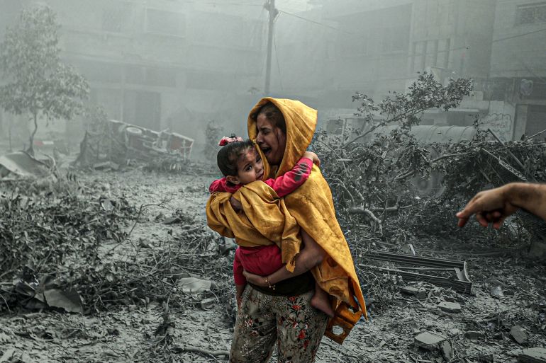 امرأة تصرخ حاملة طفلتها بعد قصف الاحتلال لحي الشيخ رضوان شمالي غزة
