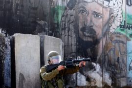 جندي إسرائيلي يوجه سلاحه نحو محتجين فلسطينيين على قيود الاحتلال بدخول المسجد الأقصى (رويترز أرشيف)